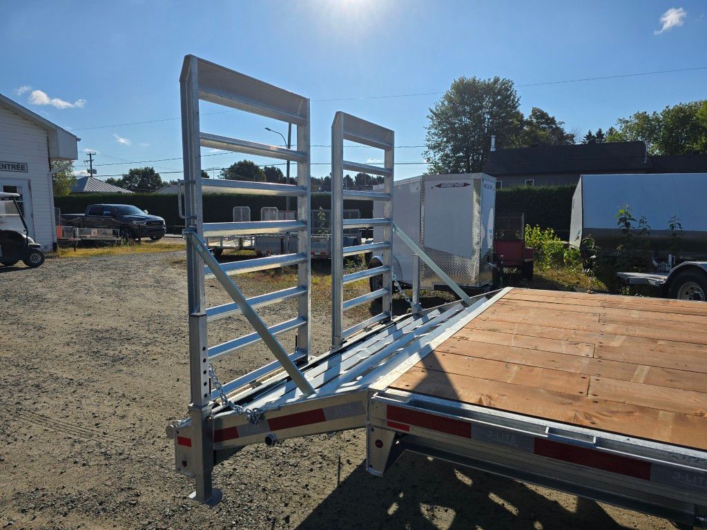 Remorque à plateau avec garde-corps en aluminium contre un ciel ensoleillé.