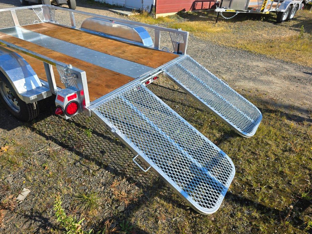 Remorque utilitaire en aluminium avec rampes en tôle diamantée sur herbe.