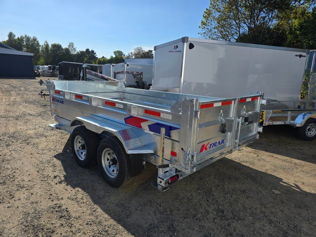 Remorque à benne basculante en aluminium à l'extérieur sur gravier avec des rayures bleues et rouges.