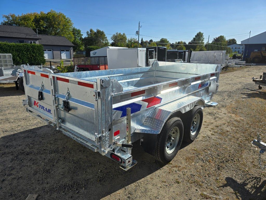 Une remorque à benne basculante en aluminium brillant garée sur du gravier, avec deux roues et une bande bleue et rouge.