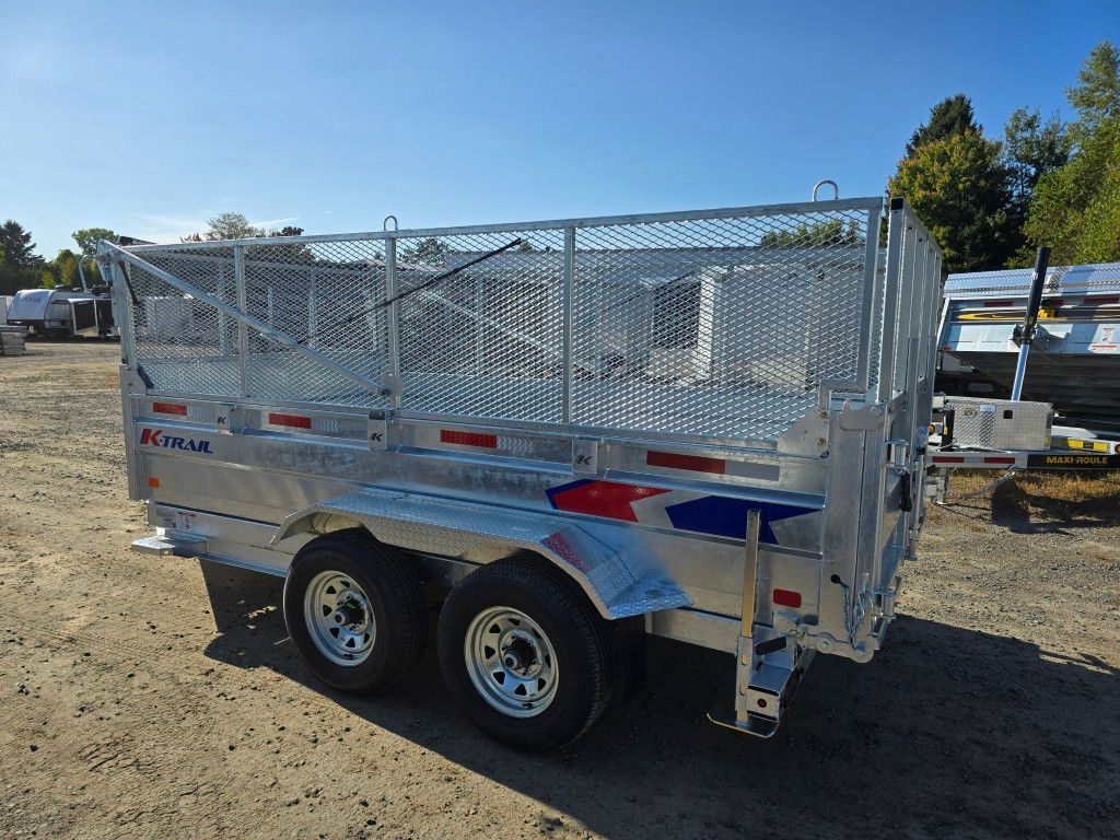 Remorque à benne basculante argentée avec roues jumelées, côtés en filet et ciel bleu dans un décor extérieur.