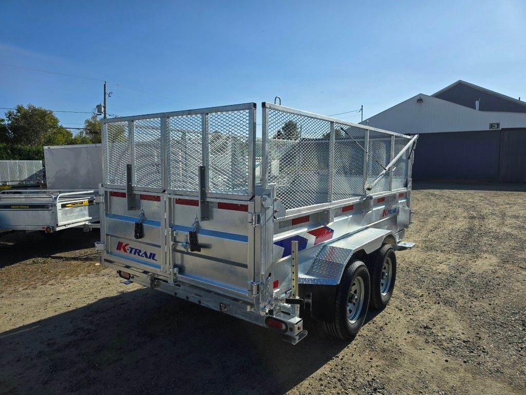 Remorque utilitaire argentée avec côtés grillagés et double essieu, garée à l'extérieur par une journée ensoleillée.