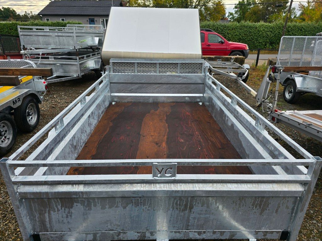 Remorque en métal galvanisé, plancher en bois brun et toit en toile blanche dans le lot d'un concessionnaire.