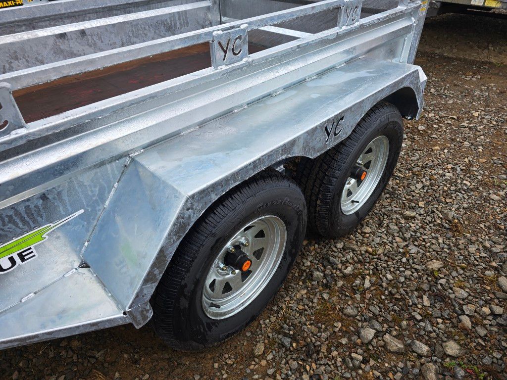 Gros plan du cadre en métal galvanisé, des roues et des pneus d'une remorque à essieu tandem ; à l'extérieur.