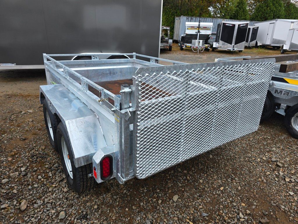 Remorque utilitaire galvanisée avec porte arrière grillagée, terrain en gravier.