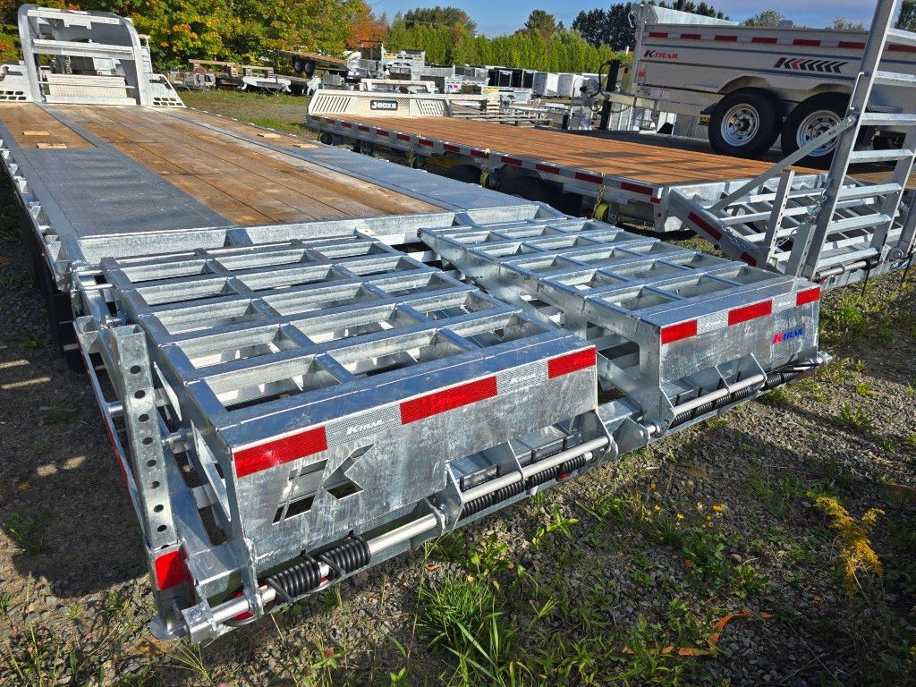 Remorque à plateau avec structure métallique, assise sur l'herbe, dans un terrain extérieur.