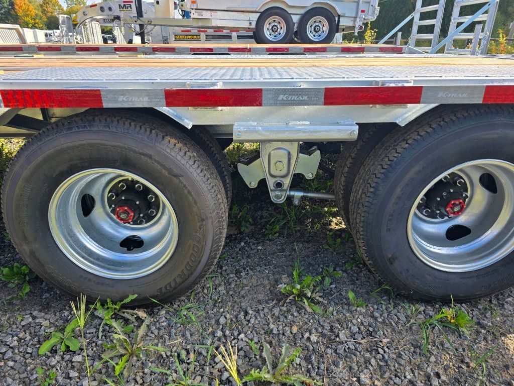 Gros plan des pneus et du train de roulement d'une remorque, montrant les roues, les pneus et un attelage.