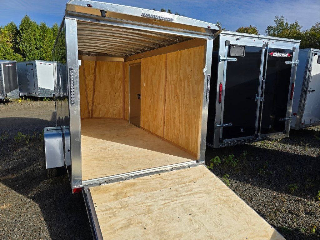 Remorque cargo ouverte avec rampe, intérieur en bois clair et extérieur en métal. Stationnée en extérieur.