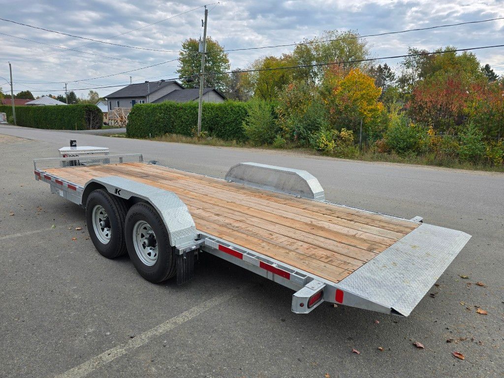 Remorque utilitaire argentée avec pont en bois sur route asphaltée.
