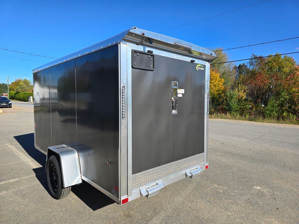 Remorque cargo noire fermée avec roue noire et garniture en aluminium contre un ciel bleu.