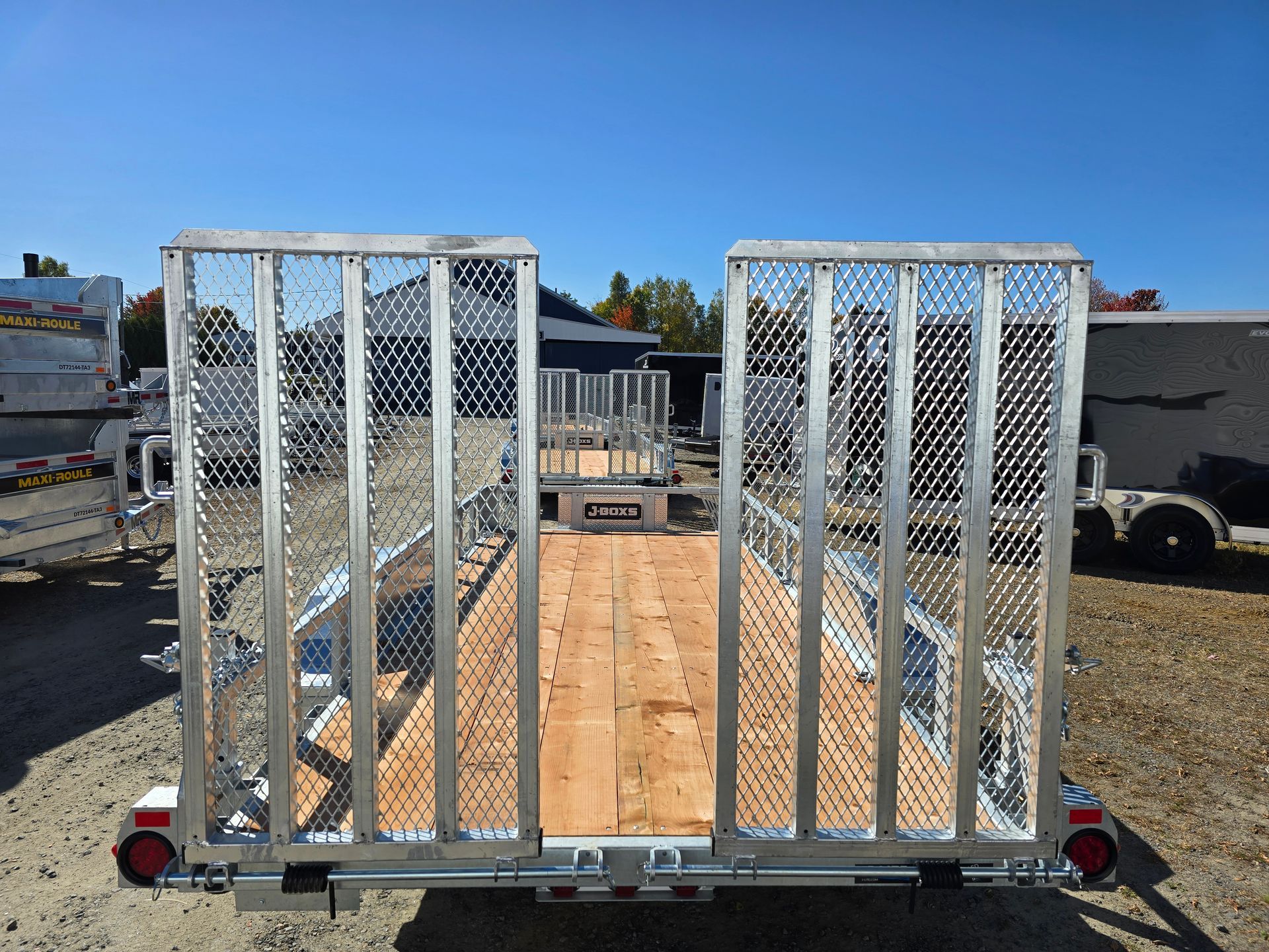 Remorque à plateau avec longerons métalliques, plateau en bois et aménagement extérieur ensoleillé.