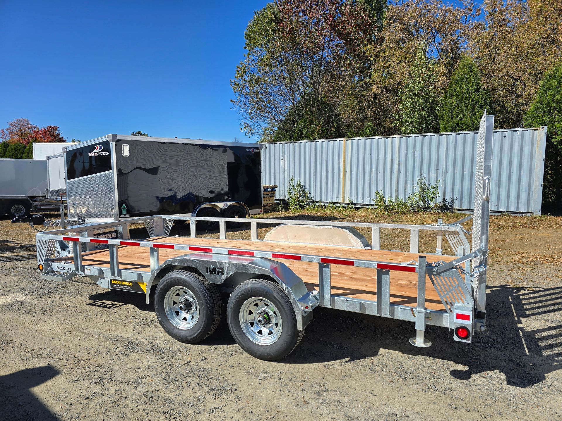 Remorque utilitaire ouverte avec terrasse en bois et balustrades, stationnée à l'extérieur.