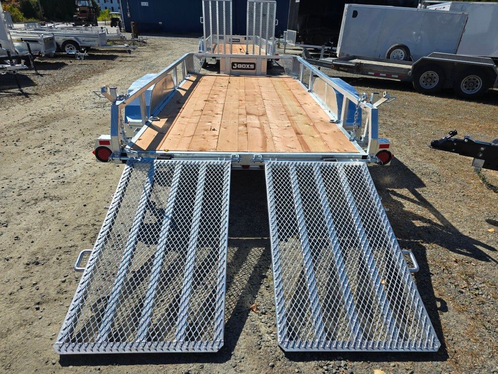 Remorque à plateau avec deux rampes métalliques, pont en bois et côtés ouverts, extérieur.