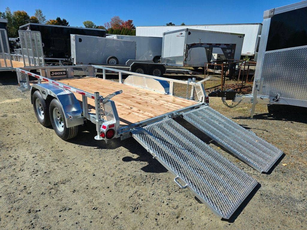 Remorque argentée avec terrasse en bois et rampes, garée à l'extérieur par une journée ensoleillée.