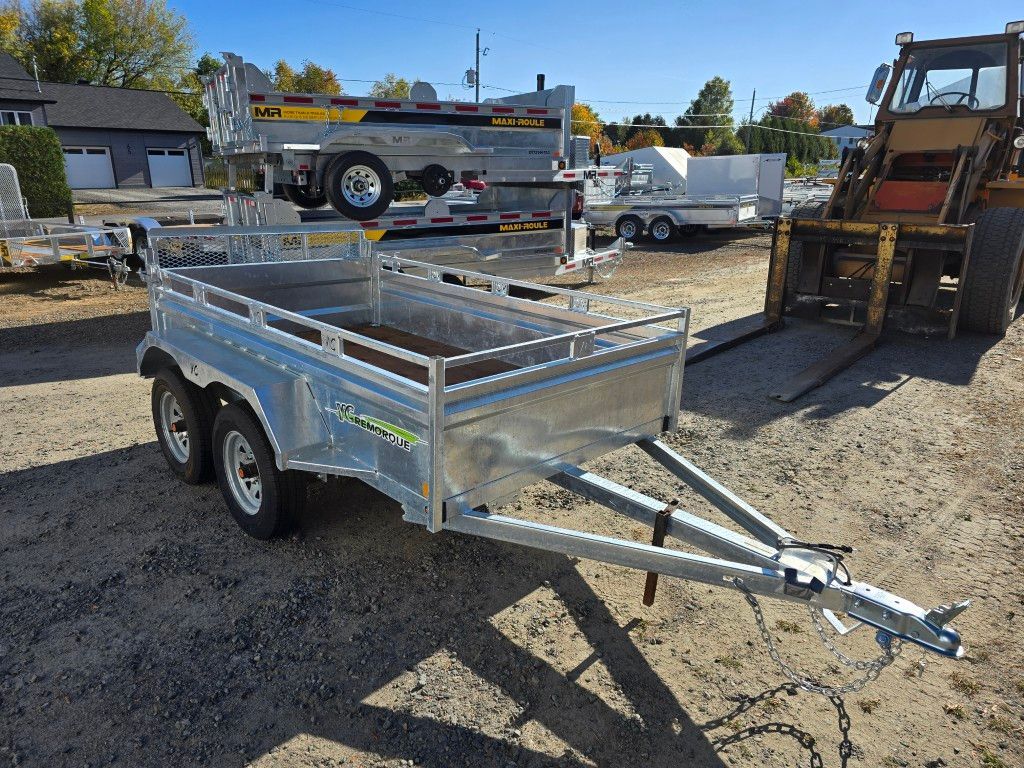 Remorque argentée avec chariot élévateur dans un terrain pavé.