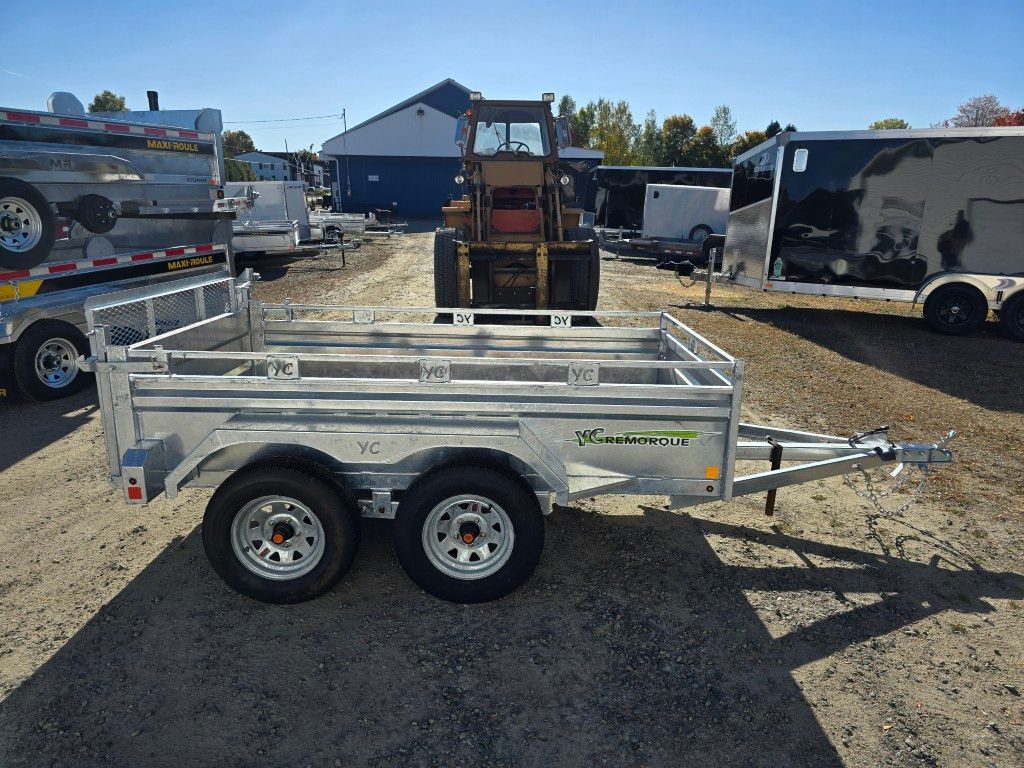 Remorque utilitaire en aluminium à roues doubles, stationnée sur asphalte, journée ensoleillée.