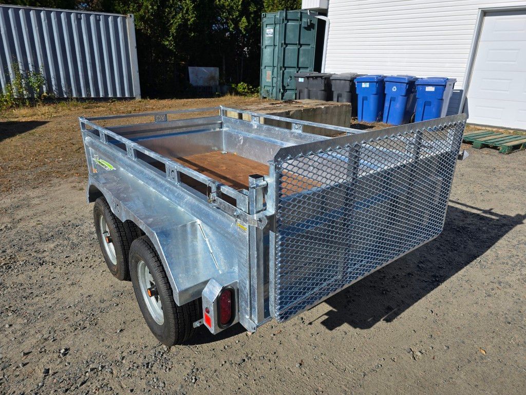 Remorque utilitaire argentée avec portail grillagé, stationnée à l'extérieur.