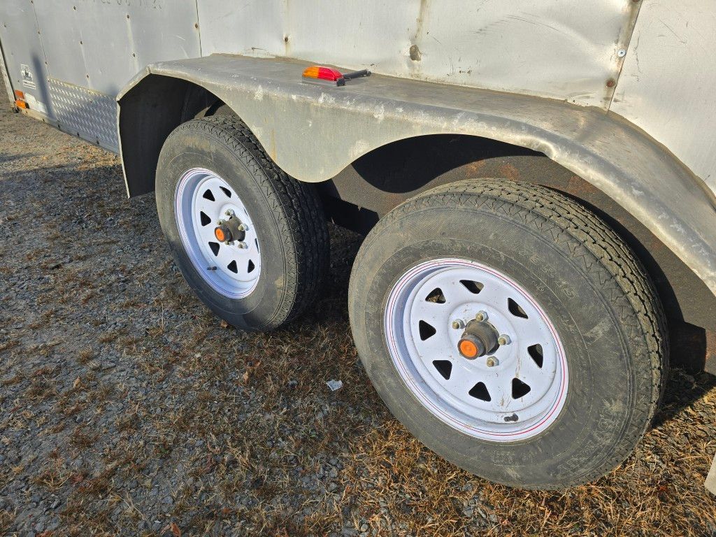 Deux pneus de remorque avec jantes blanches et pneus usés sur un garde-boue gris.