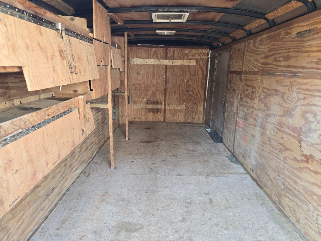 Intérieur d'une remorque cargo avec parois en contreplaqué et étagères, semblant vide.