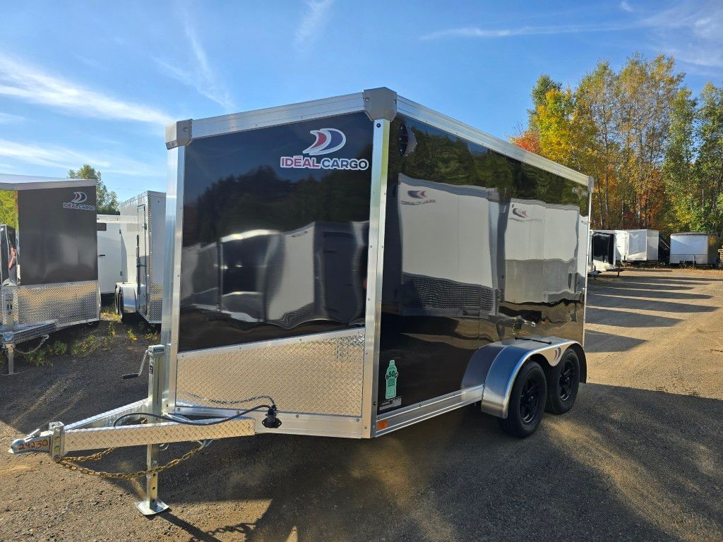 Remorque fermée noire avec des accents argentés, garée à l'extérieur sous un ciel bleu.