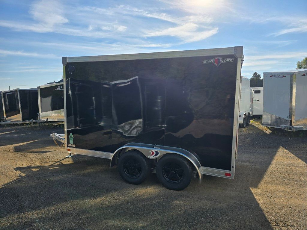 Remorque cargo fermée noire avec roues noires par une journée ensoleillée.