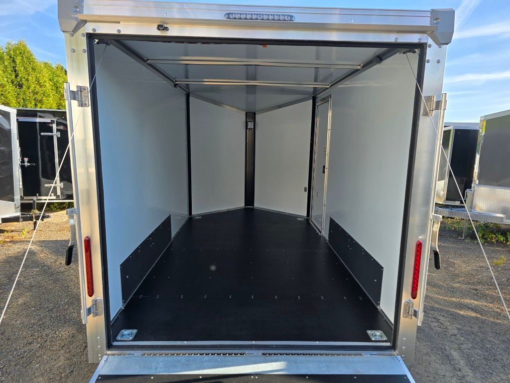 À l'intérieur d'une remorque cargo vide et argentée avec un plancher noir et des murs blancs.