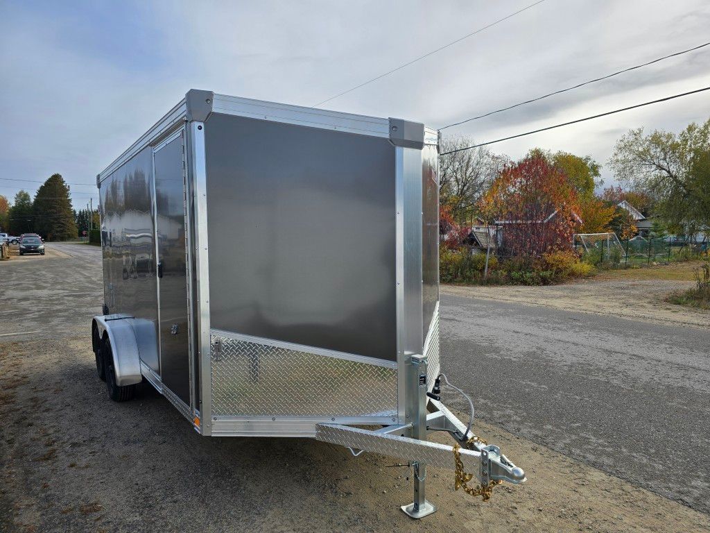 Remorque cargo fermée, grise et argent avec garniture en plaque de diamant, à l'extérieur sur asphalte, journée nuageuse.