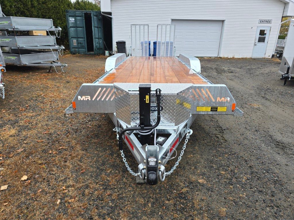 Remorque plateau en métal argenté avec plancher en bois, garée à l'extérieur, au soleil.