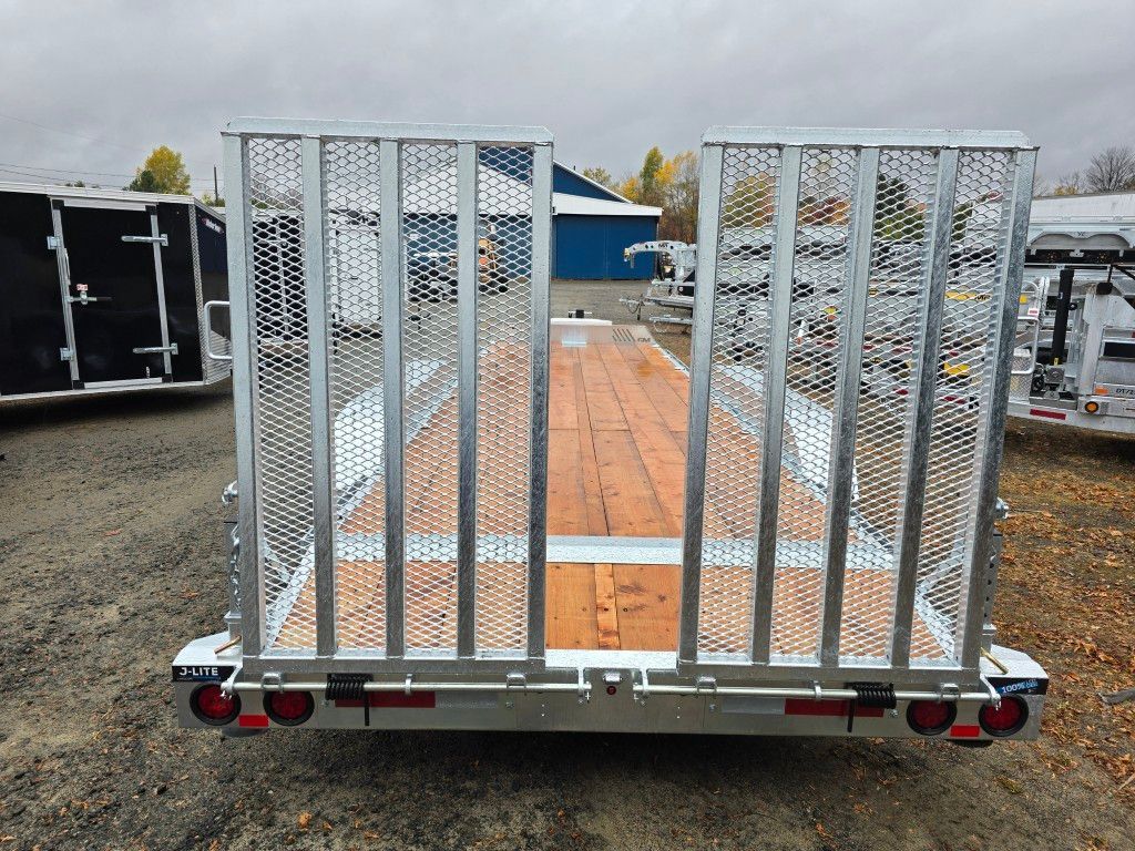 Une caravane avec un portail en métal et une terrasse en bois, garée dehors par temps nuageux.