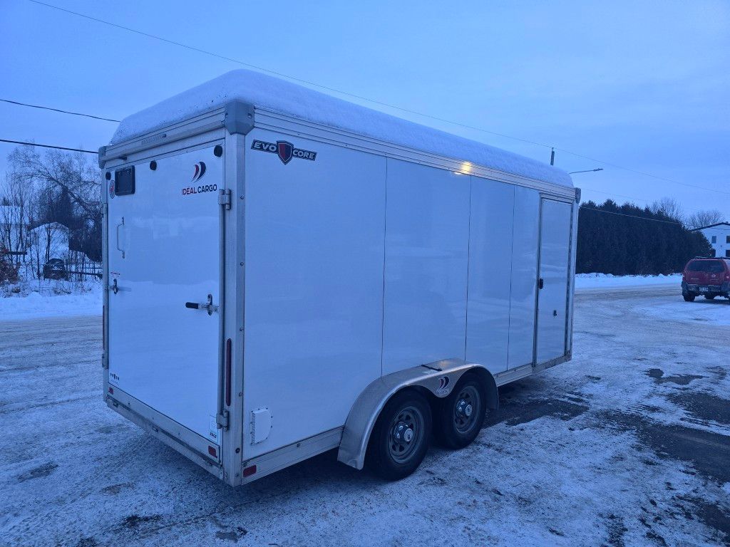 Remorque blanche fermée garée à l'extérieur dans un décor enneigé.