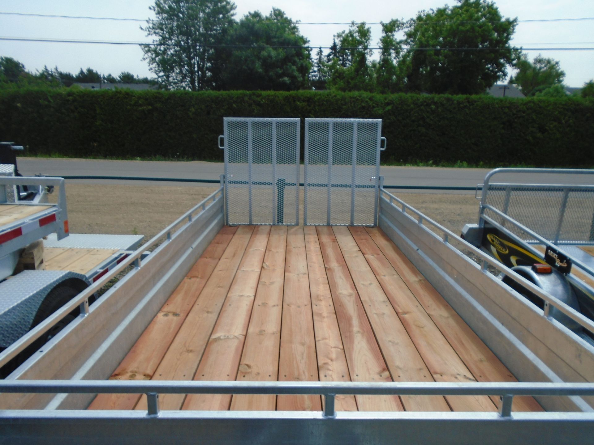 Remorque à plateau avec plancher en bois, côtés en métal et porte en métal.