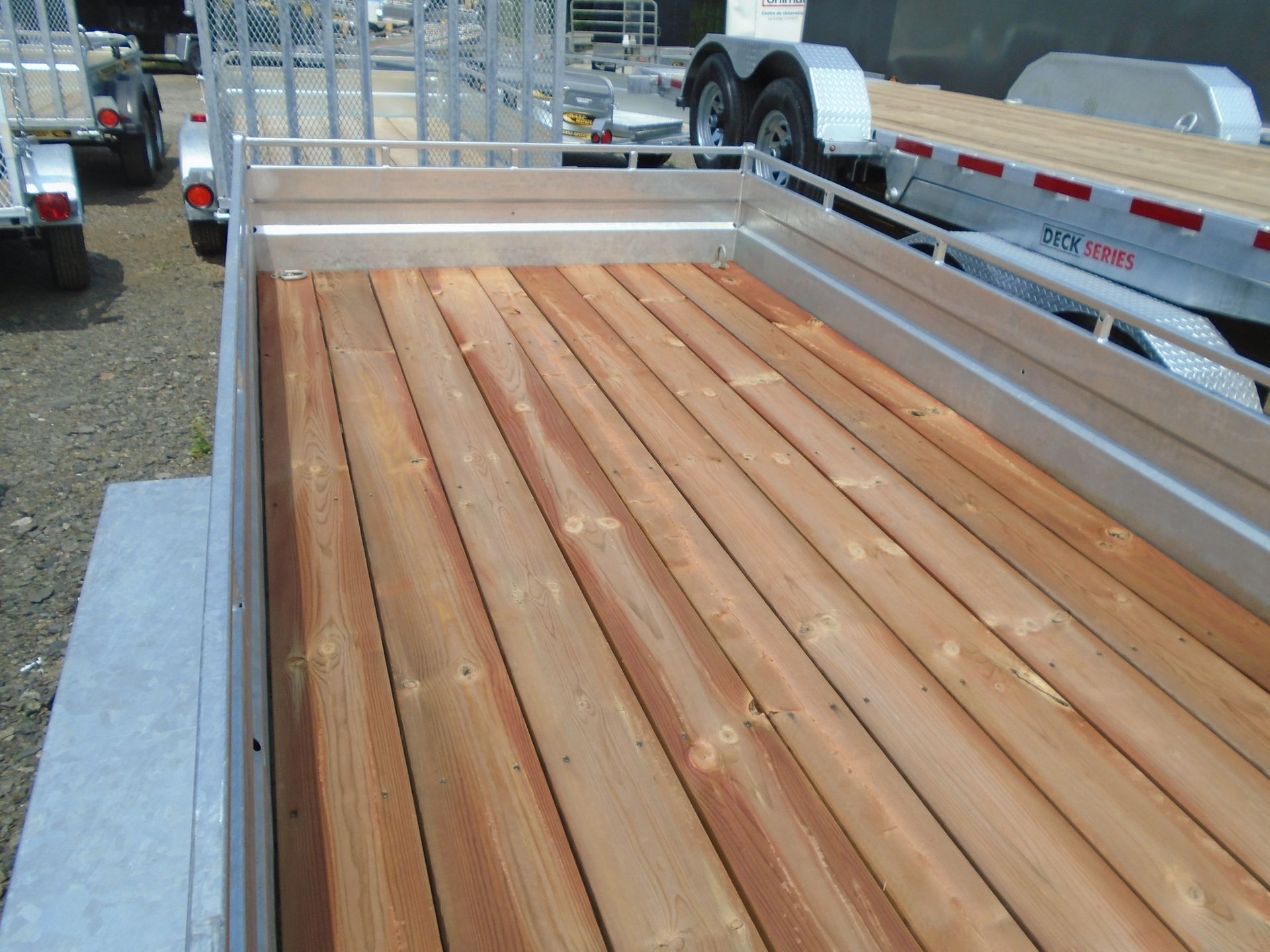 Remorque plateau en bois avec rails en aluminium dans un décor extérieur.