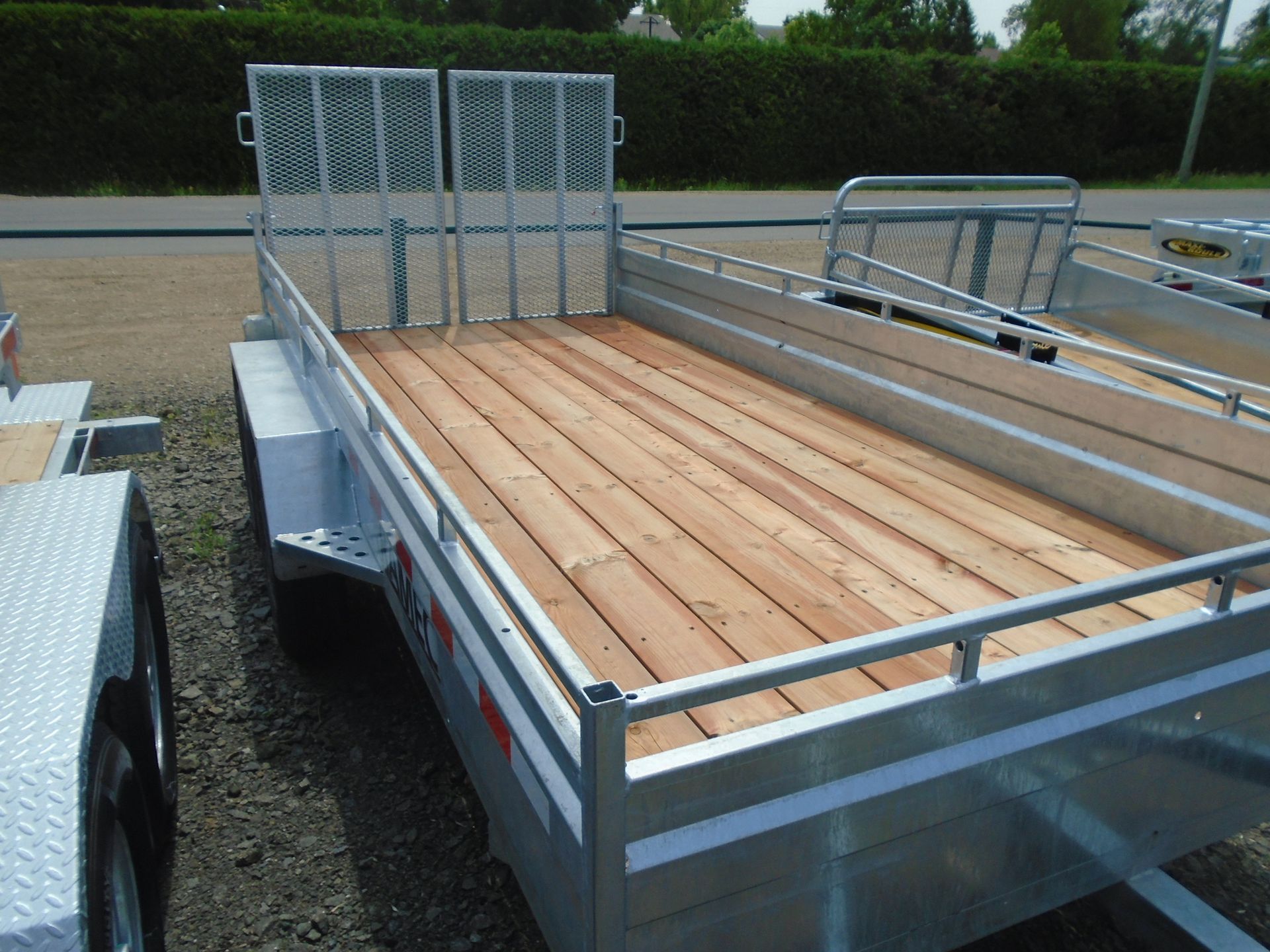 Remorque utilitaire ouverte avec pont en bois, rails latéraux et porte arrière.