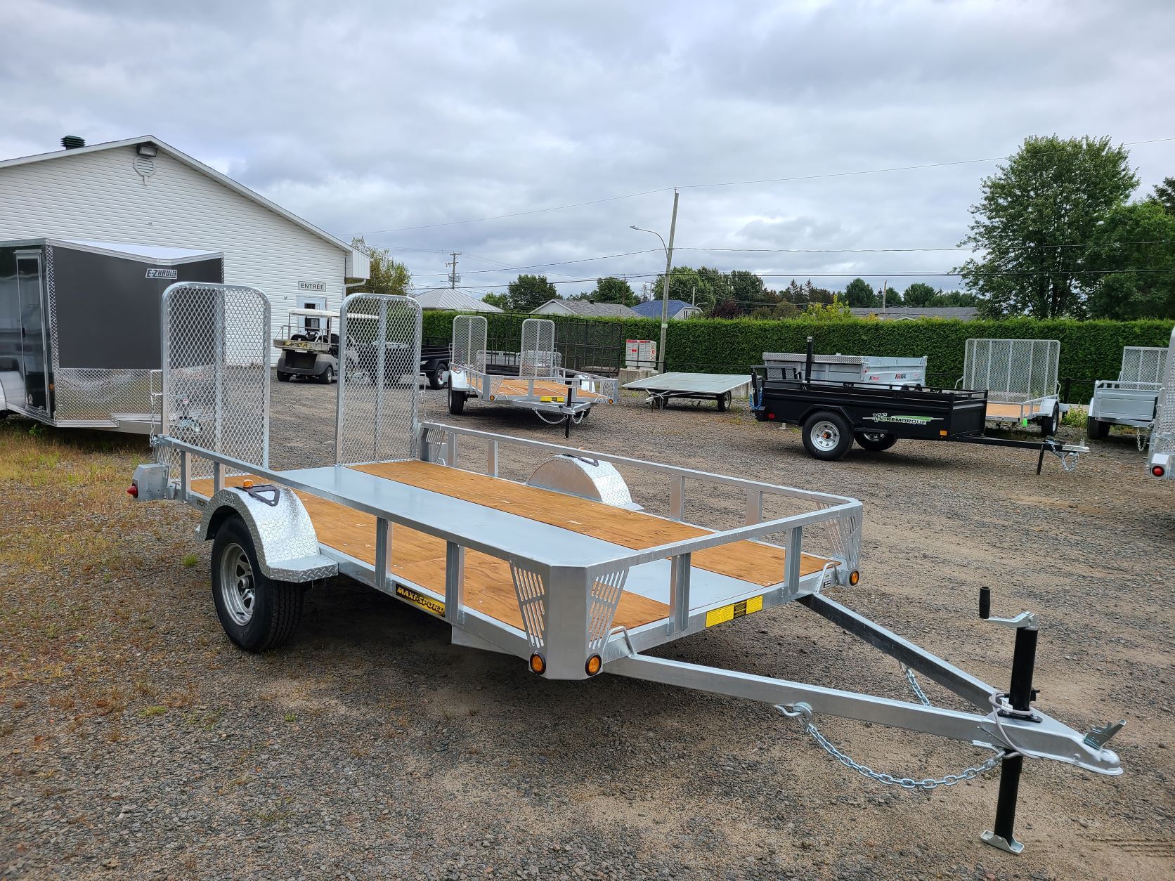 Une remorque est garée sur un terrain en gravier devant un bâtiment.