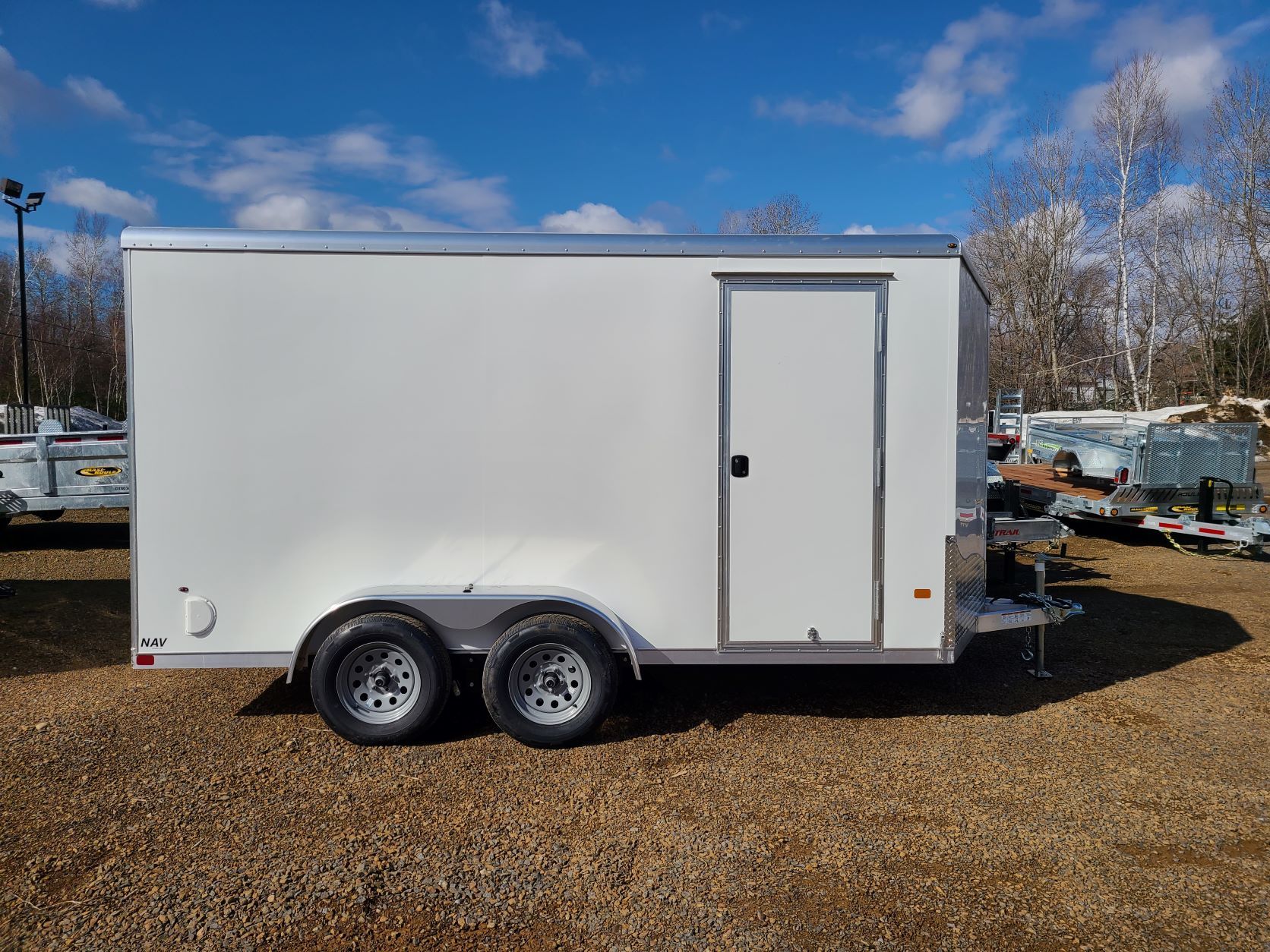 Une remorque blanche est garée sur un terrain en gravier.