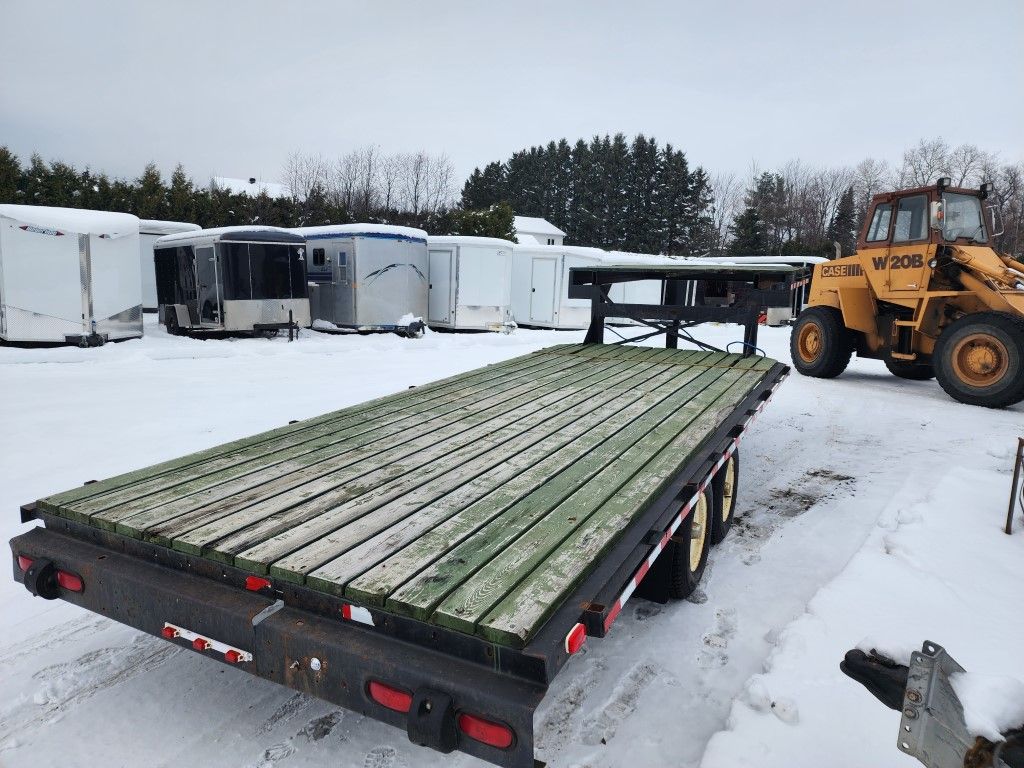 Un tracteur jaune est garé à côté d'une remorque dans la neige.