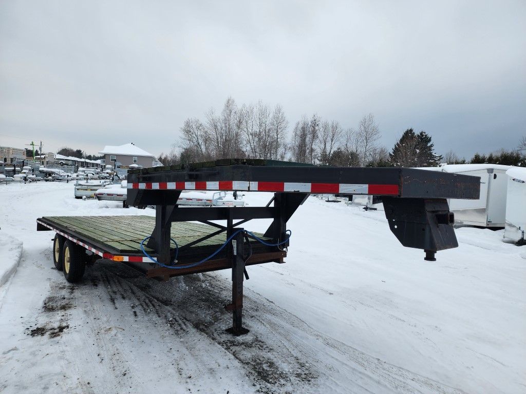 Une remorque à plateau est garée sur un parking enneigé