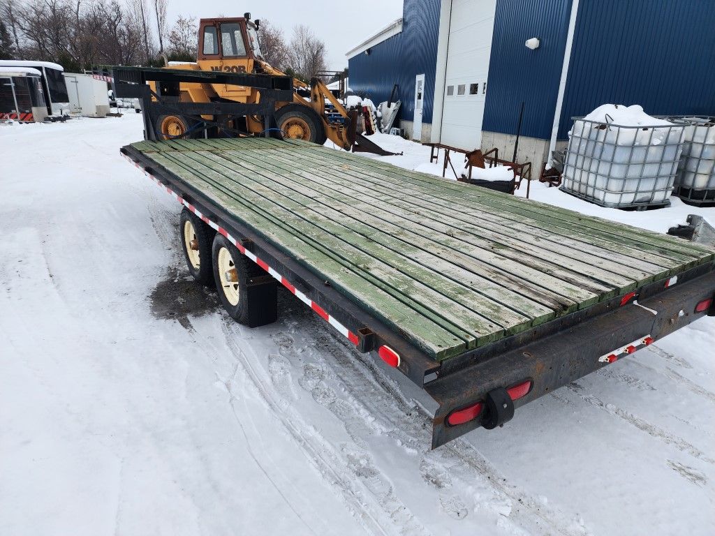 Un camion à plateau est garé dans la neige devant un bâtiment.