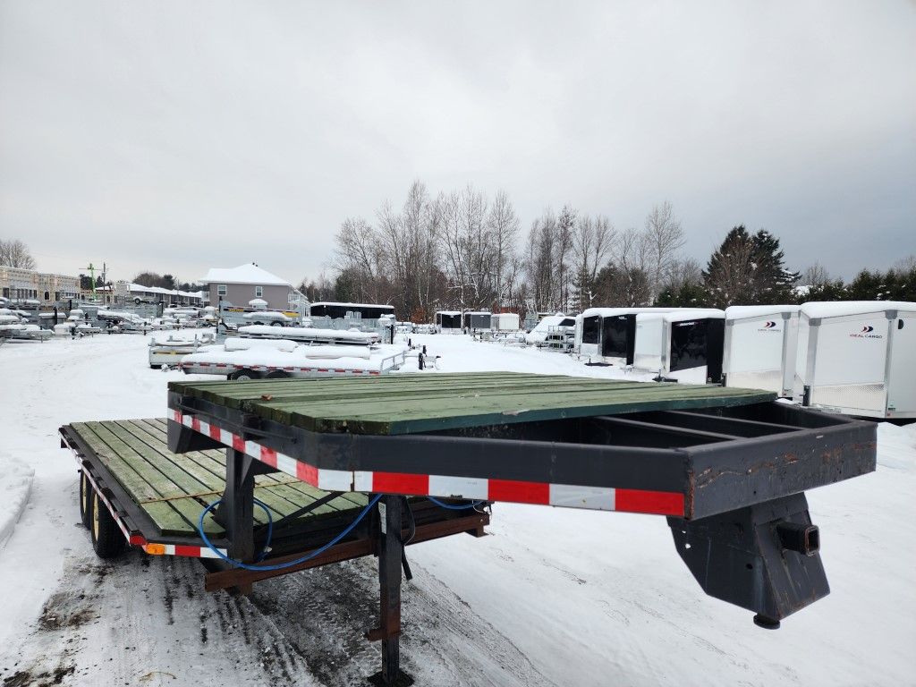 Une remorque à plateau est garée sur un parking enneigé