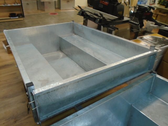 Un grand récipient en métal est posé sur un plancher en bois