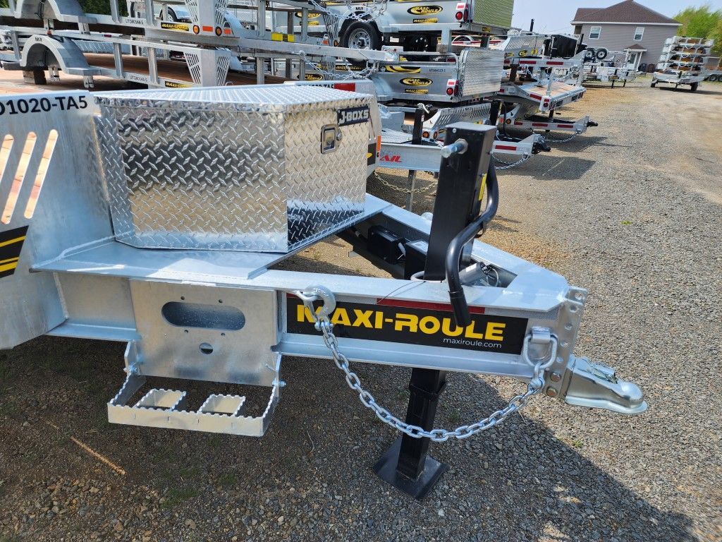 Une remorque maxi-roule est garée sur un terrain en gravier