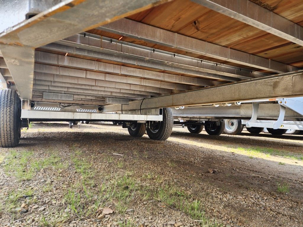 Une remorque avec un plancher en bois est garée sur un chemin de terre.