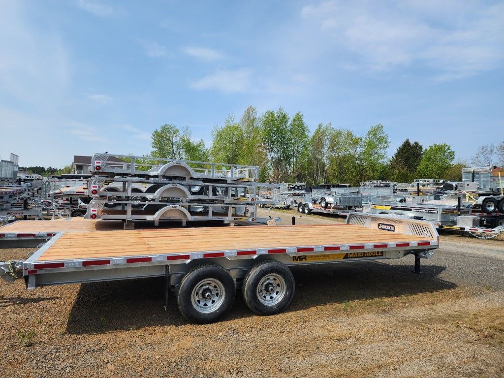 Une remorque à plateau est garée sur un terrain en gravier.