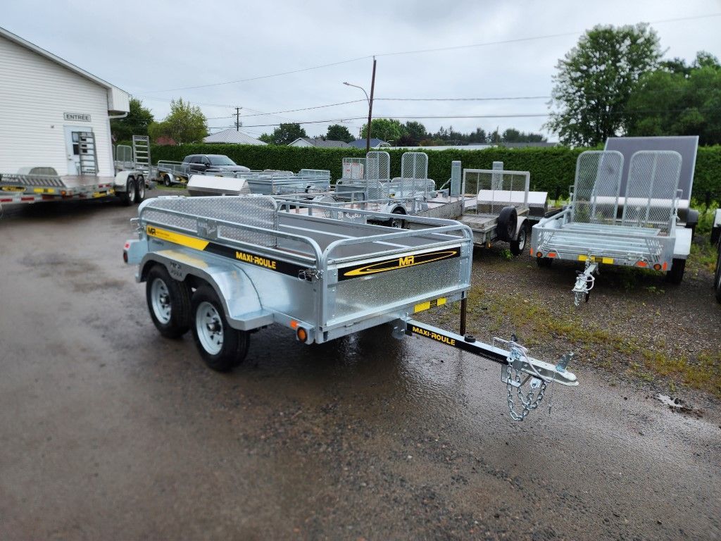 Une remorque est garée sur un parking à côté d'un bâtiment.
