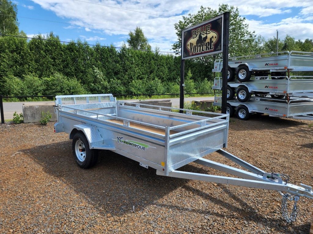 Une remorque est garée sur un terrain en gravier à côté d'un panneau.