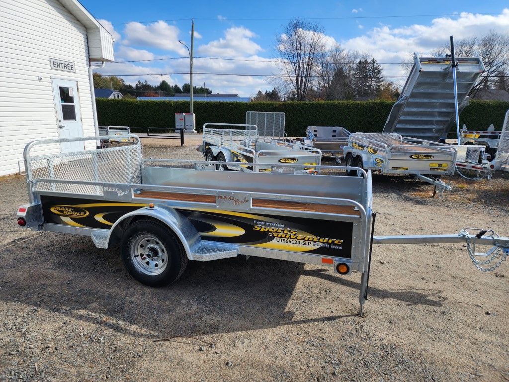 Une remorque est garée sur un terrain en gravier devant un bâtiment.