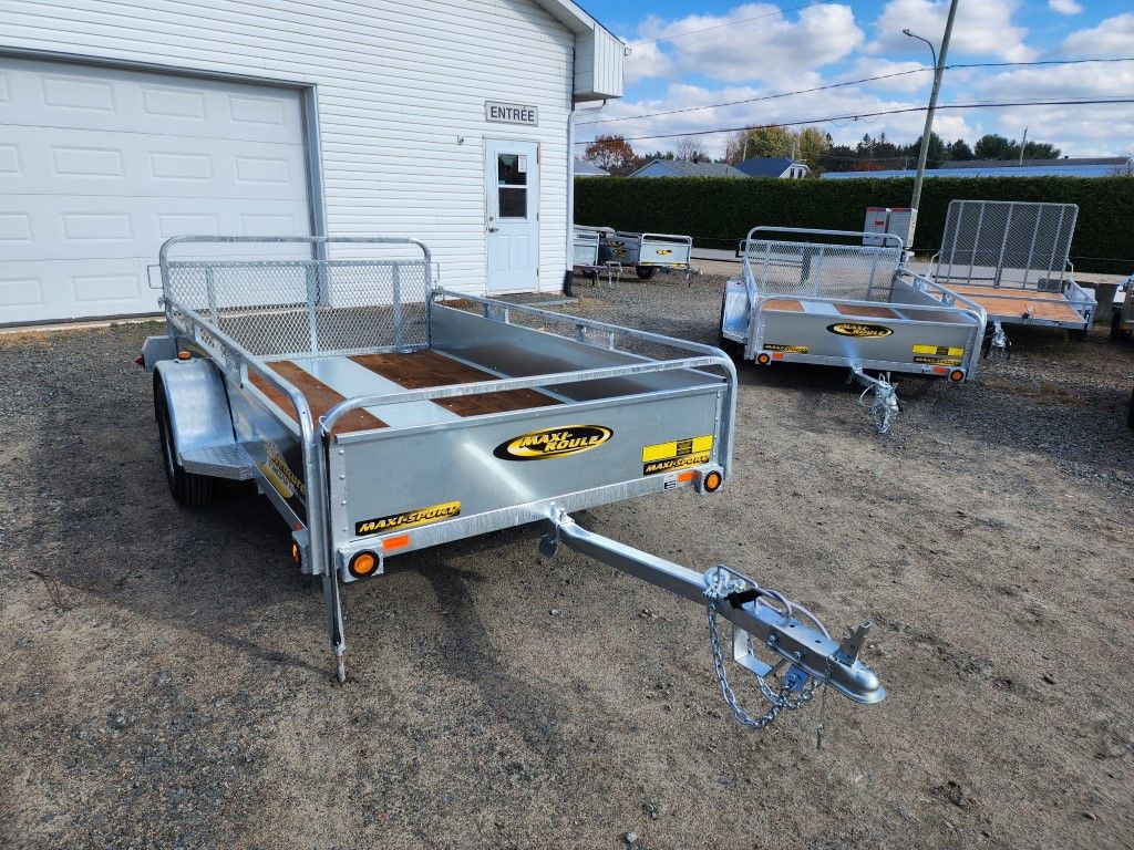 Une remorque est garée devant un garage.