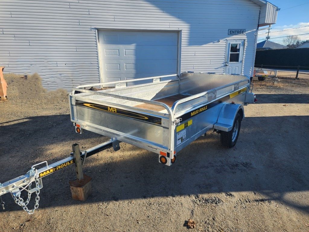 Remorque utilitaire argentée garée à l'extérieur d'un bâtiment par une journée ensoleillée.