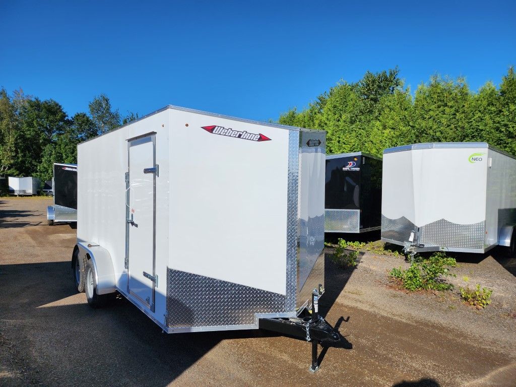 Une remorque blanche est garée sur un parking à côté d'autres remorques.