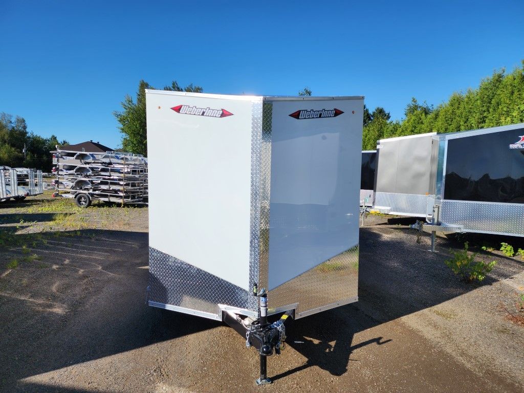 Une remorque blanche est garée sur le bord de la route